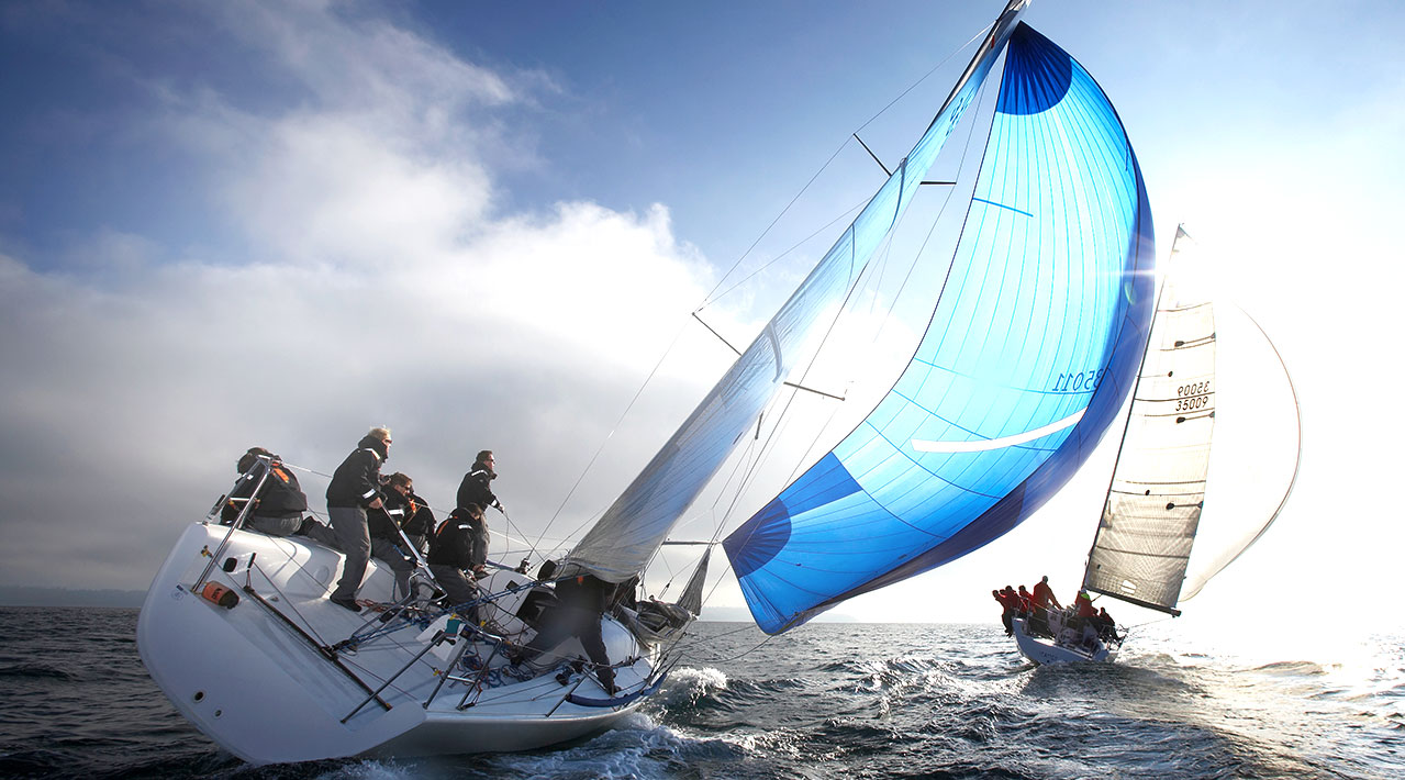 Two racing sailboats compete in a regatta on a sunny, cold day. 